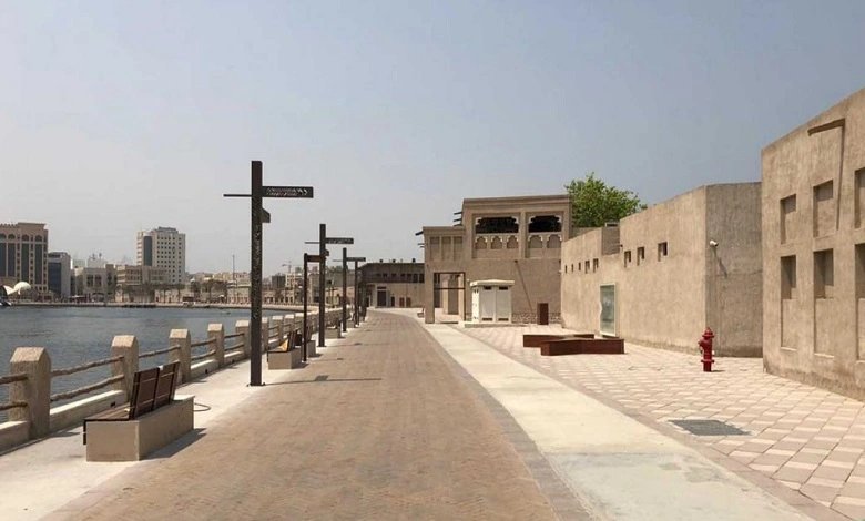 Traditional-style pedestrian walkway along Dubai Creek in Al Shindagha Historic District with restored heritage buildings.