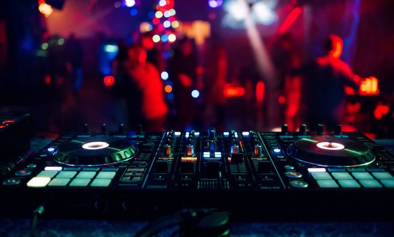 DJ mixing console at a lively Amsterdam nightclub with colorful lights and dancing crowd