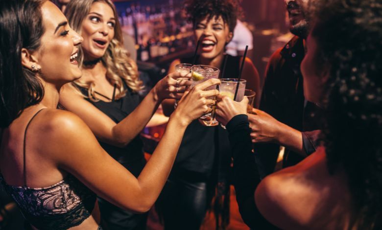 Group of friends toasting drinks and smiling at a nightclub in amsterdam