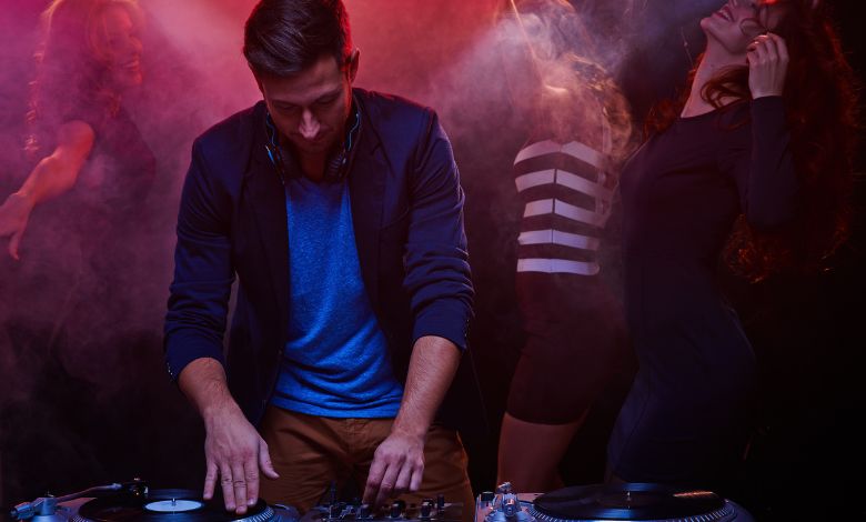 DJ performing in a vibrant Amsterdam nightclub with people dancing in the background