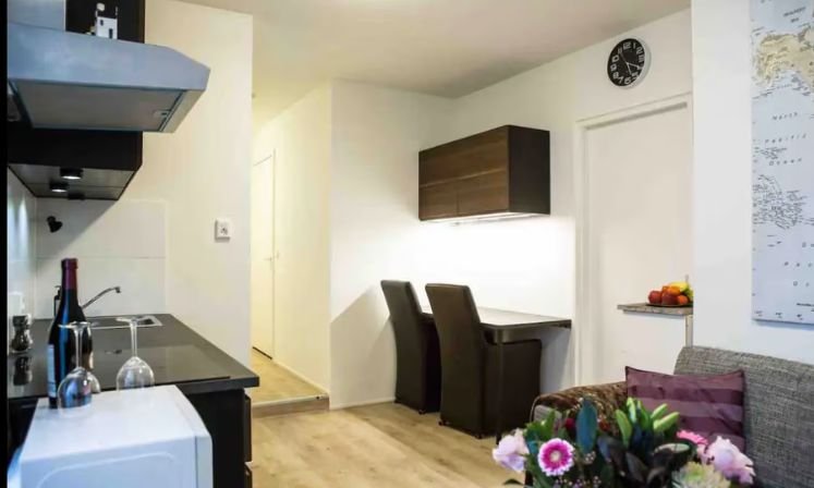 A kitchen in Ljmuiden Apartments featuring a microwave, refrigerator, and a dining table for a cozy atmosphere.