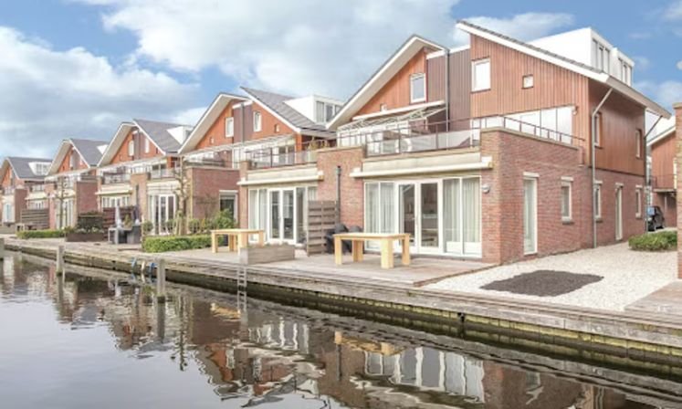 Uitgeest Serviced Apartments by the water, showcasing a charming row of houses alongside a dock.