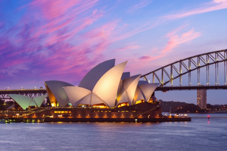 Sydney Opera House and Harbour Bridge at sunset with pink clouds.