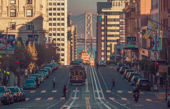 Cable car on steep San Francisco street with Bay Bridge