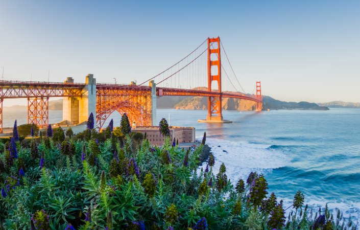Golden Gate Bridge at sunset with waves below