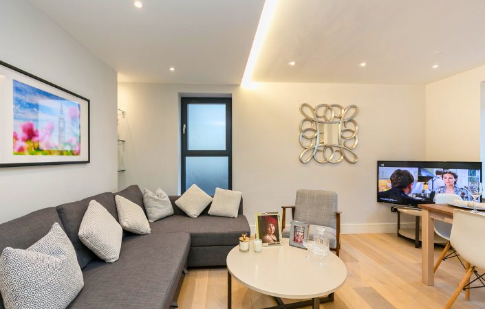 Modern serviced apartment in Notting Hill with stylish grey sofa, TV, and elegant interior decor.