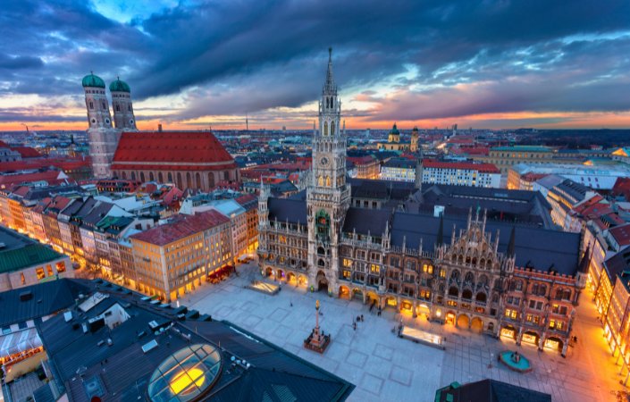 Panoramic aerial view of Marienplatz square in Munich during sunset with historic buildings and church towers.