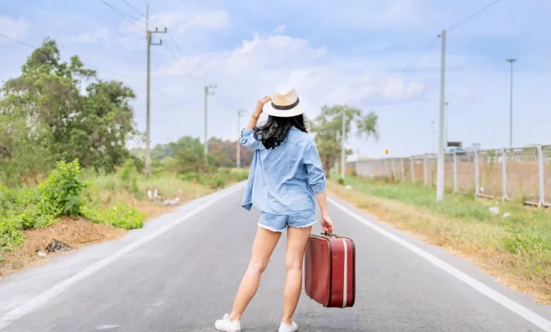 Woman travelling with a suitcase on a road