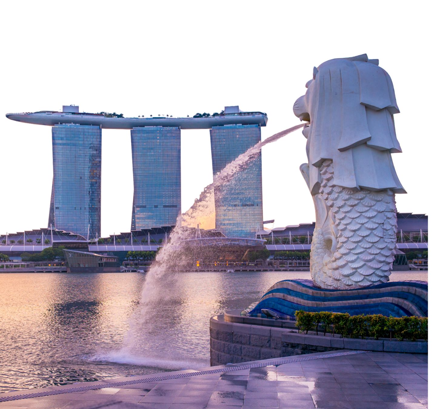 Merlion statue at Merlion Park with water spouting from its mouth, and Marina Bay Sands in the background in Singapore during Sunset.