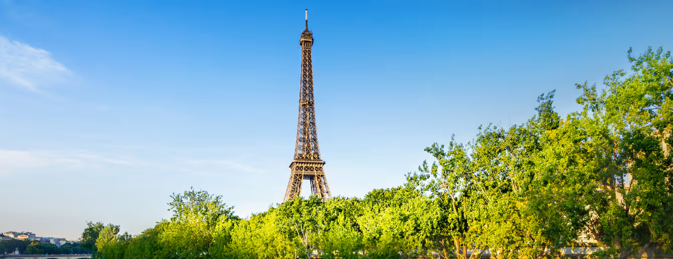 Eiffel Tower overlooking the Paris skyline on a sunny day — an iconic view during a Paris holiday or romantic trip to Paris.