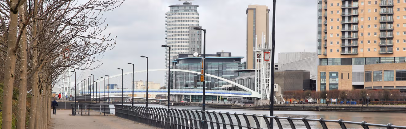 Salford Quays waterfront with modern buildings and pedestrian bridge in Manchester.